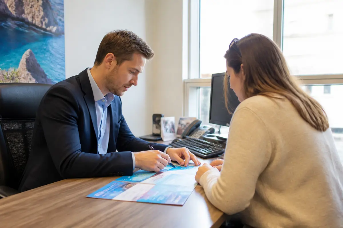 Un agent général de ventes conseille un client dans un bureau lumineux avec documents.