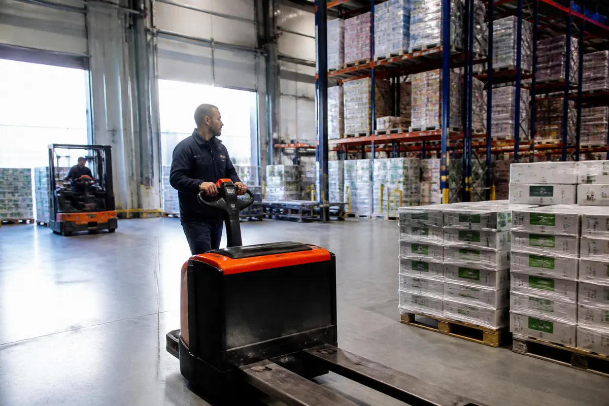 Travailleur déplaçant des palettes dans la plateforme logistique de Metro avec un transpalette électrique