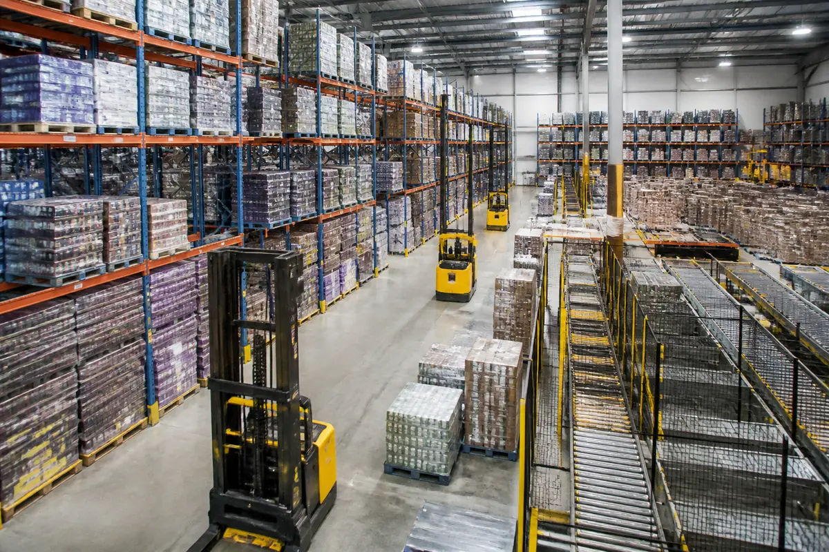 Chariots élévateurs dans l'entrepôt de logistique Ouest d'Auchan, palettes empilées
